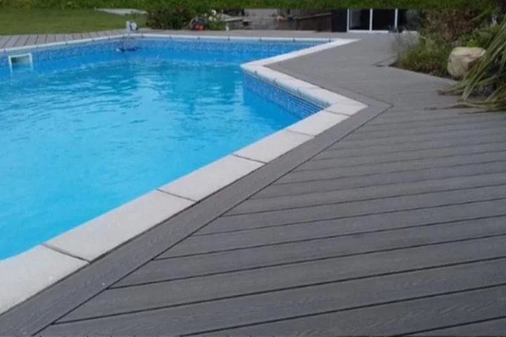 Grey WPC decking laid around a swimming pool with a coping stone edge