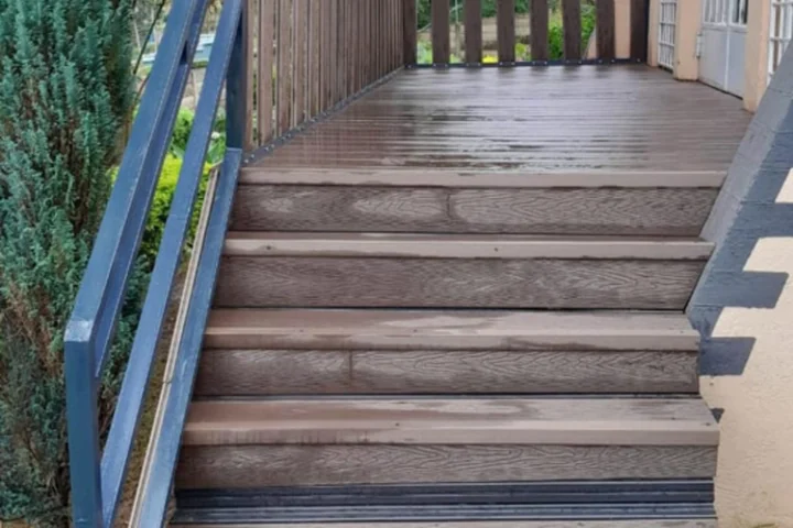 WPC deck with matching steps and a painted steel railing at a house entrance